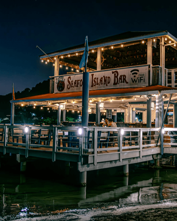 Captain Jack's Seafood Island Bar lit up at night over the Caribbean Sea