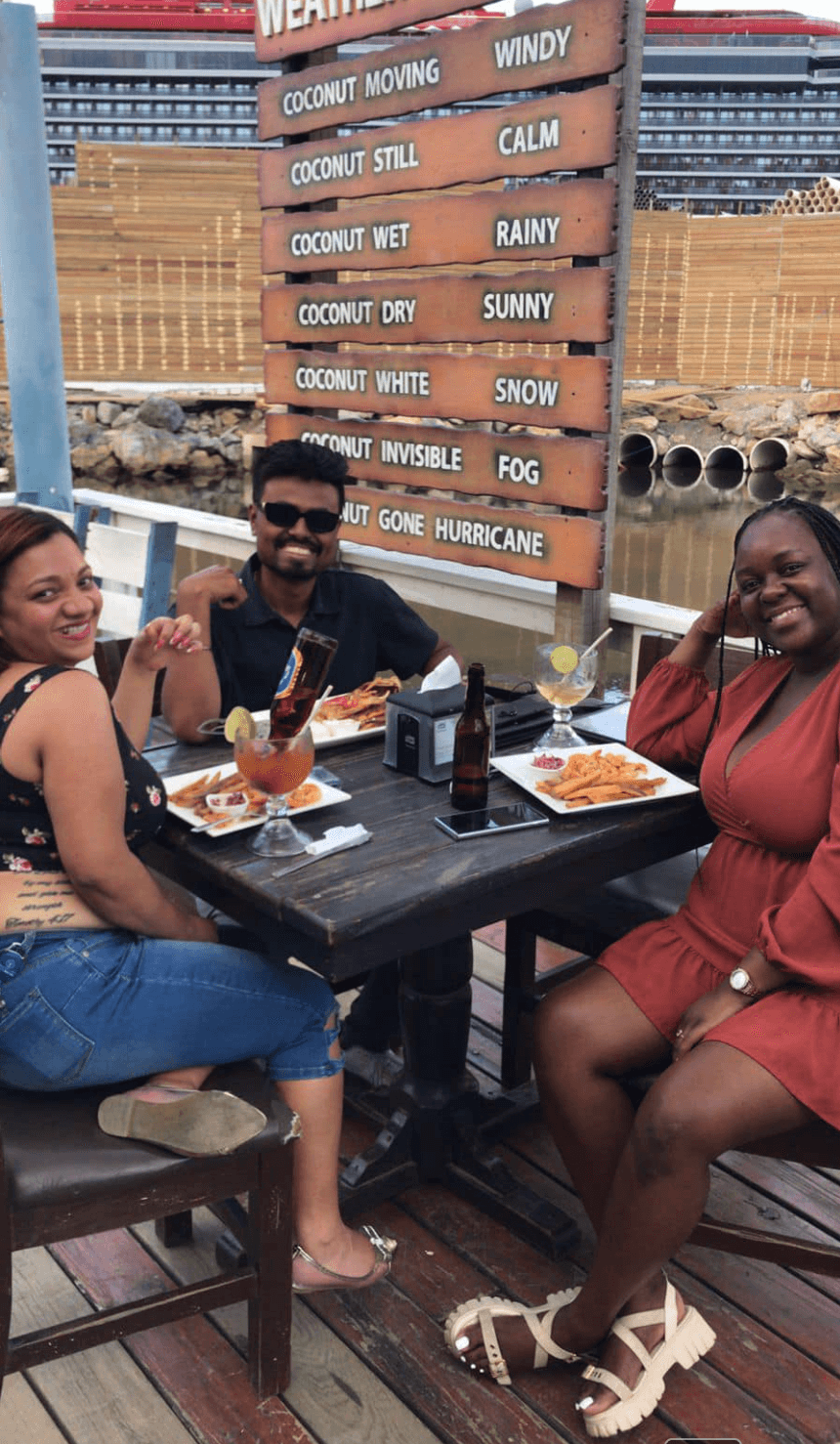 Happy guests dining on Captain Jack's patio with cruise ship in background